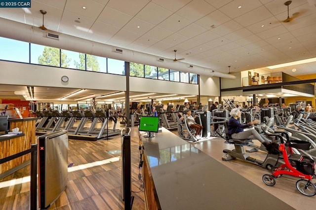 exercise room with ceiling fan and a high ceiling