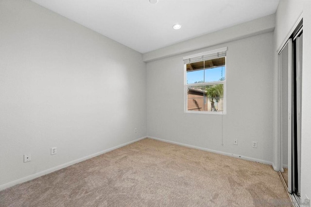 unfurnished bedroom featuring light colored carpet and a closet