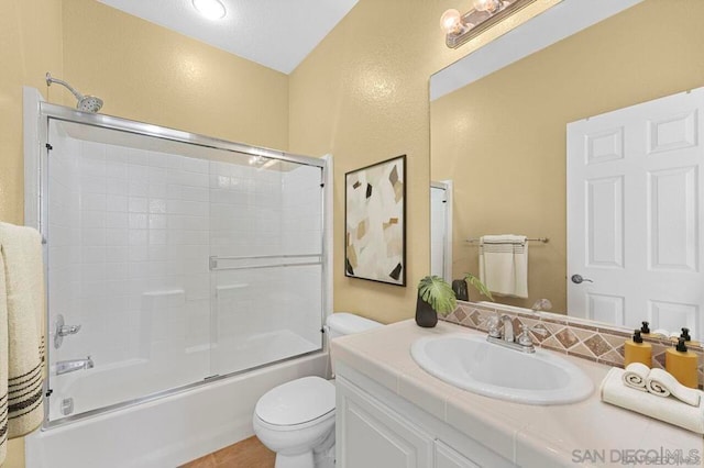 full bathroom featuring vanity, shower / bath combination with glass door, and toilet