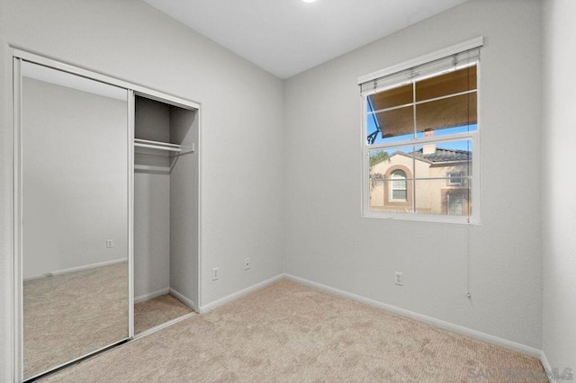 unfurnished bedroom with light colored carpet and a closet