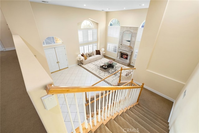 staircase featuring a towering ceiling and a fireplace