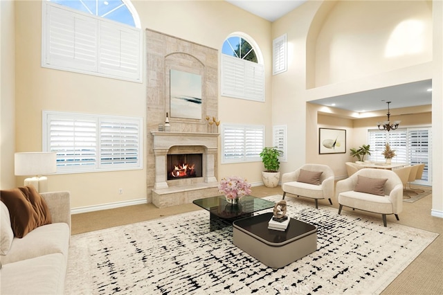 living room with a towering ceiling, a fireplace, carpet flooring, and a notable chandelier