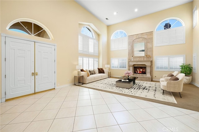 foyer entrance featuring a premium fireplace, a towering ceiling, and light tile patterned floors