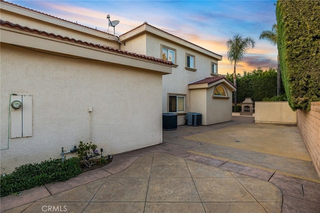 property exterior at dusk featuring a patio and central air condition unit