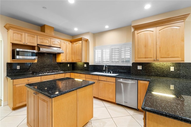 kitchen featuring dark stone countertops, appliances with stainless steel finishes, a center island, and sink