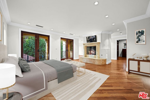 bedroom featuring wood-type flooring, crown molding, access to exterior, and a high end fireplace