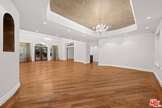 interior space featuring hardwood / wood-style flooring, a tray ceiling, crown molding, and a notable chandelier