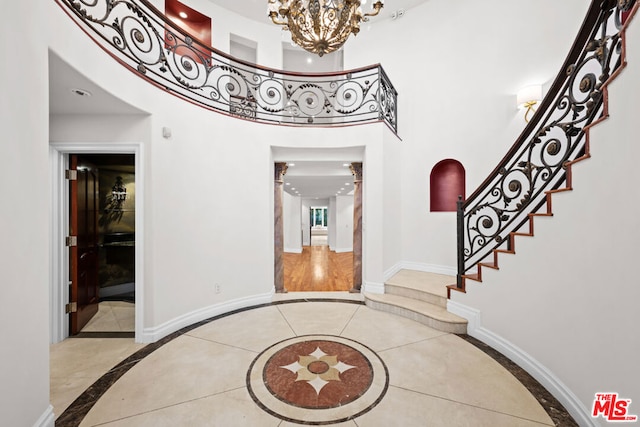 foyer featuring an inviting chandelier and a towering ceiling