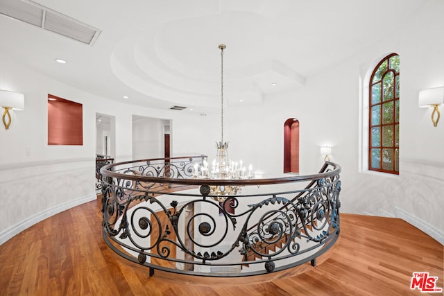 corridor with hardwood / wood-style floors and a chandelier