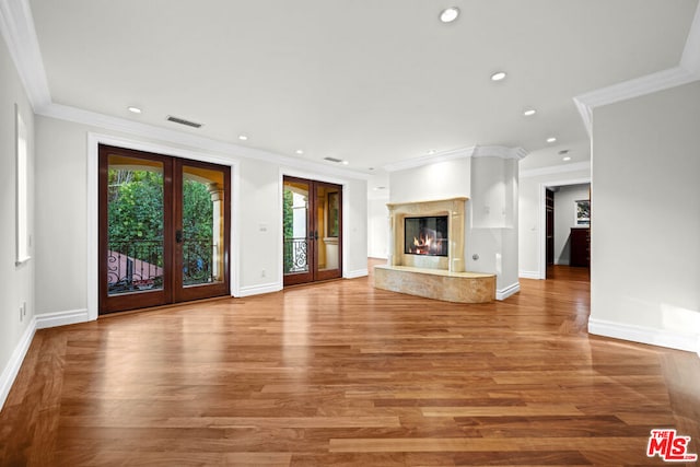 unfurnished living room with french doors, a high end fireplace, crown molding, and wood-type flooring