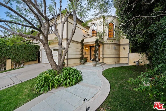 view of front facade featuring a balcony, a garage, and a front lawn