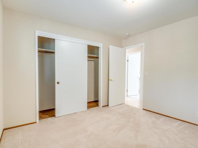 unfurnished bedroom with light carpet and a closet