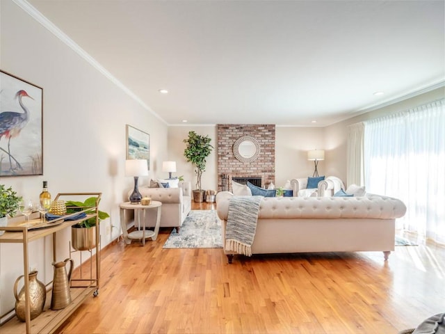 living room featuring a brick fireplace, ornamental molding, and light wood-type flooring