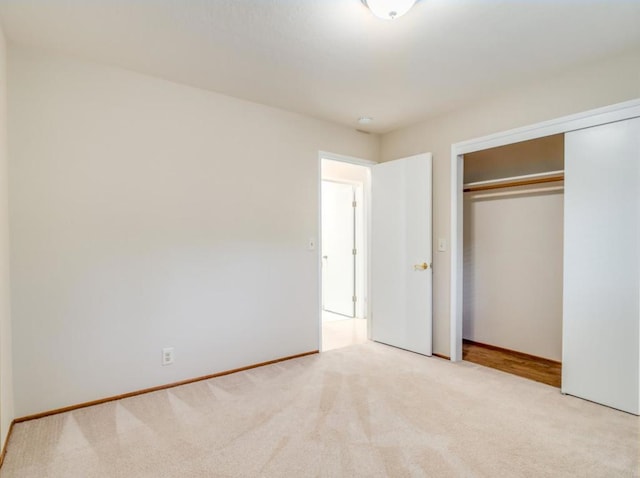 unfurnished bedroom featuring light carpet and a closet