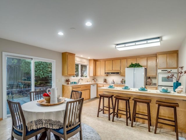 kitchen featuring white appliances, light brown cabinetry, and sink