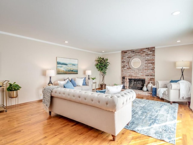 living room featuring a brick fireplace, ornamental molding, and light wood-type flooring