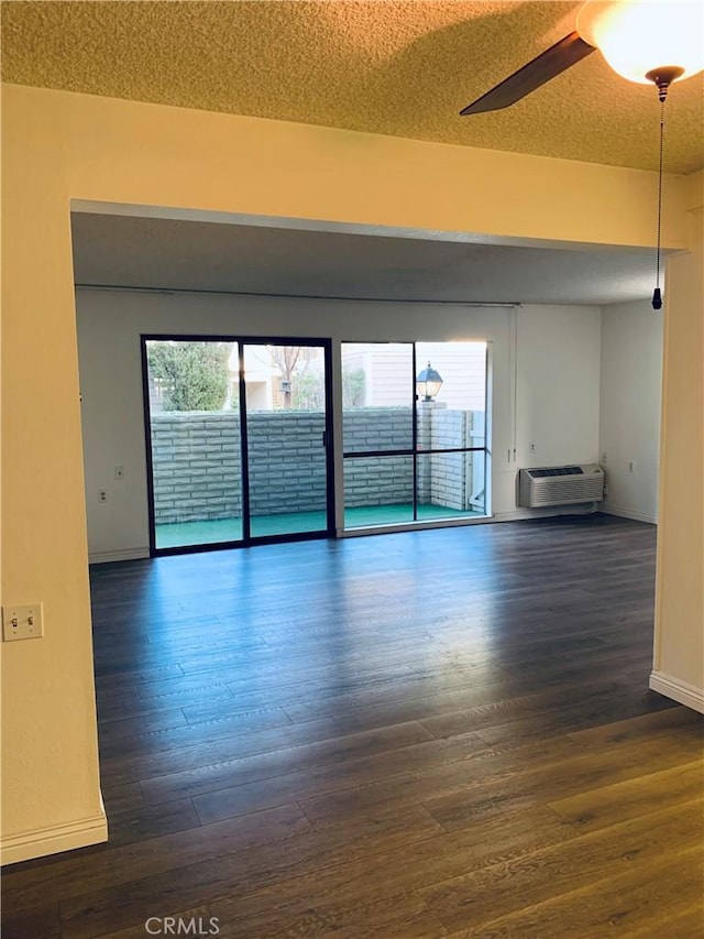 spare room with dark hardwood / wood-style flooring, ceiling fan, a wall mounted AC, and a textured ceiling