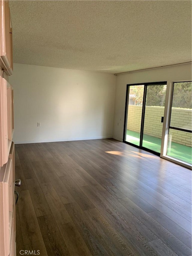 spare room featuring dark hardwood / wood-style floors and a textured ceiling