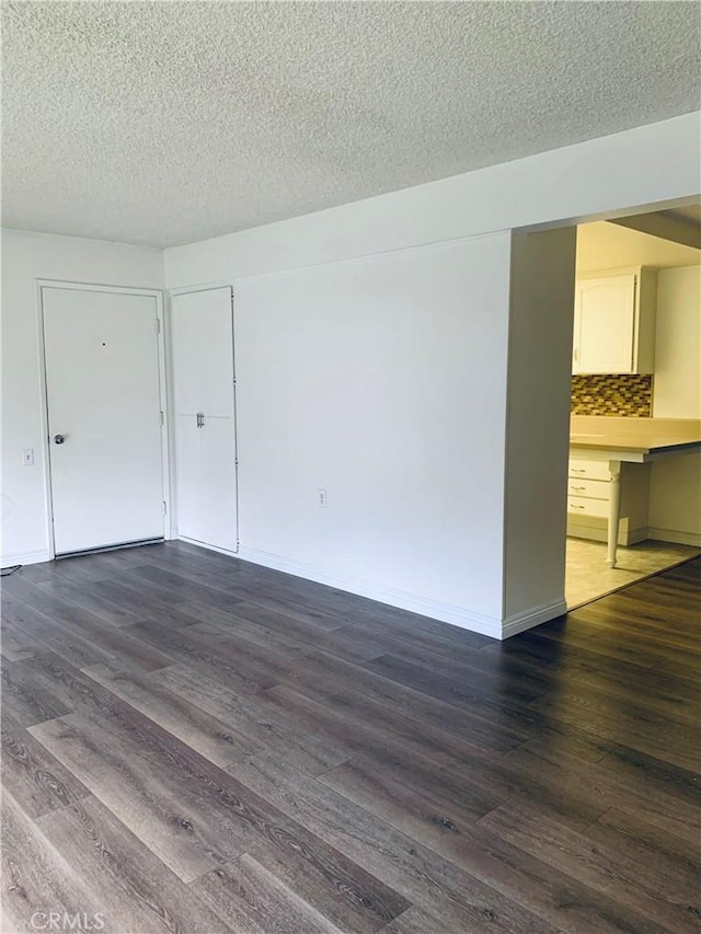 empty room with dark hardwood / wood-style floors and a textured ceiling