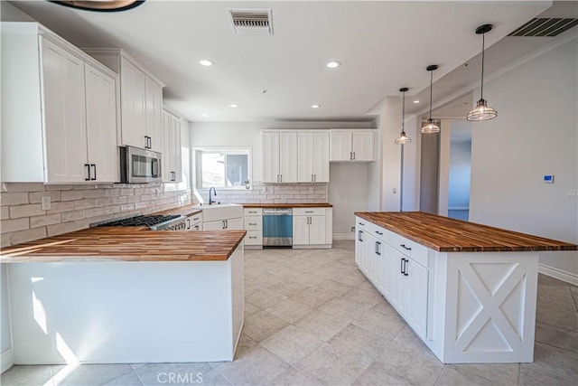 kitchen with butcher block counters, pendant lighting, stainless steel appliances, decorative backsplash, and white cabinets