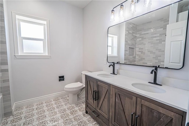 bathroom with tiled shower, vanity, and toilet