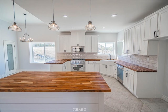 kitchen featuring wooden counters, stainless steel appliances, decorative light fixtures, and white cabinets