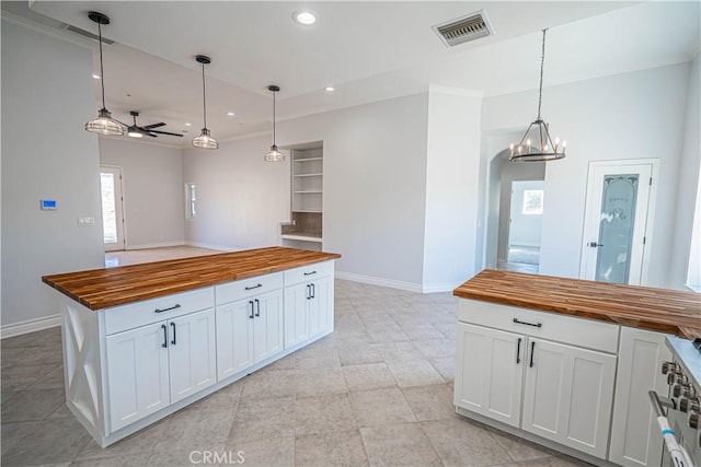 kitchen with white cabinetry, hanging light fixtures, high end range, wood counters, and built in shelves