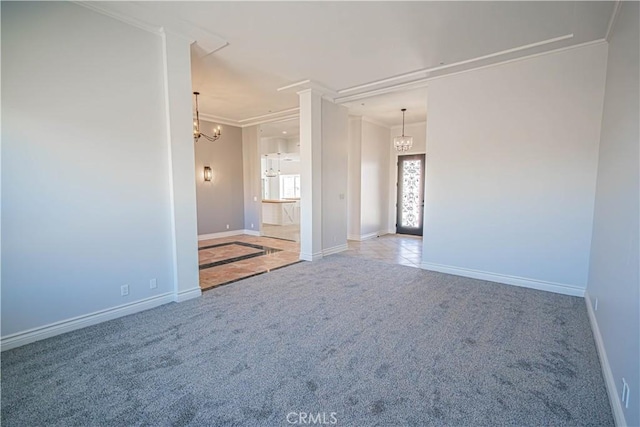 carpeted spare room featuring ornamental molding and a notable chandelier