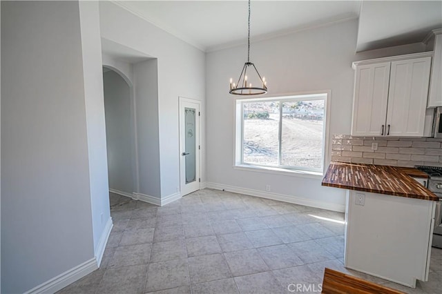 unfurnished dining area with ornamental molding, light tile patterned floors, and an inviting chandelier