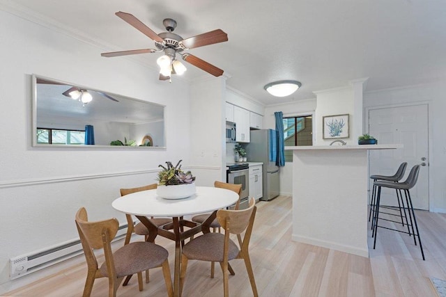 dining area featuring crown molding, a baseboard radiator, plenty of natural light, and light wood-type flooring