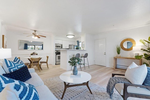 living room featuring a wealth of natural light, ornamental molding, and light wood-type flooring