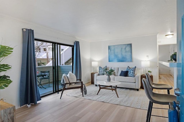 living room with ornamental molding and light hardwood / wood-style floors