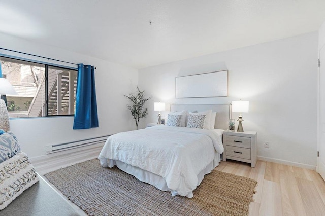 bedroom with a baseboard heating unit and light hardwood / wood-style floors