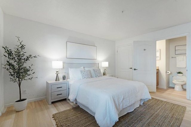 bedroom with connected bathroom and light hardwood / wood-style floors