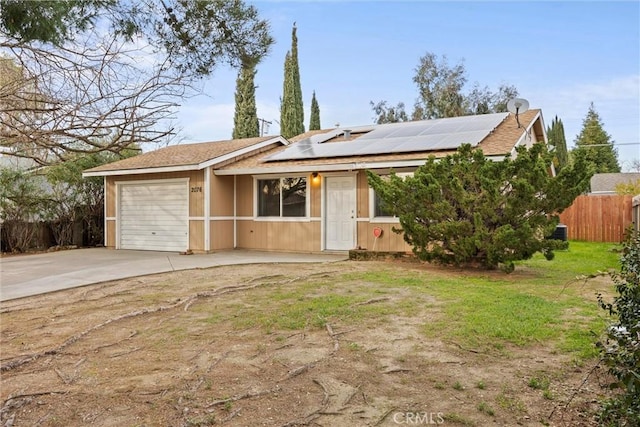 single story home with a garage, a front yard, and solar panels