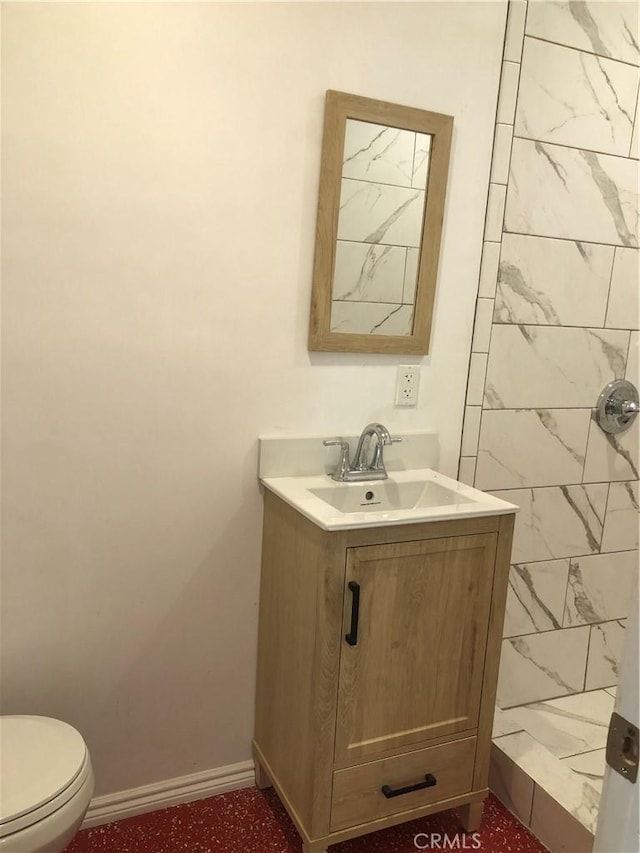 bathroom with tiled shower, vanity, and toilet