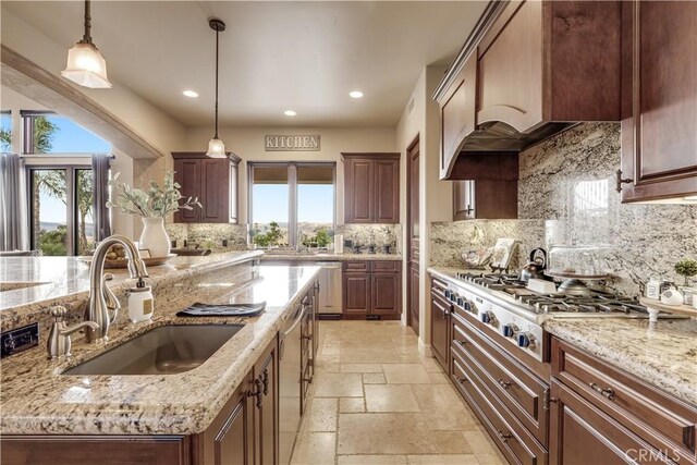 kitchen with light stone counters, hanging light fixtures, and sink