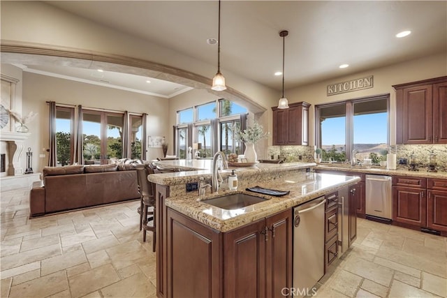 kitchen with sink, a center island with sink, backsplash, and decorative light fixtures