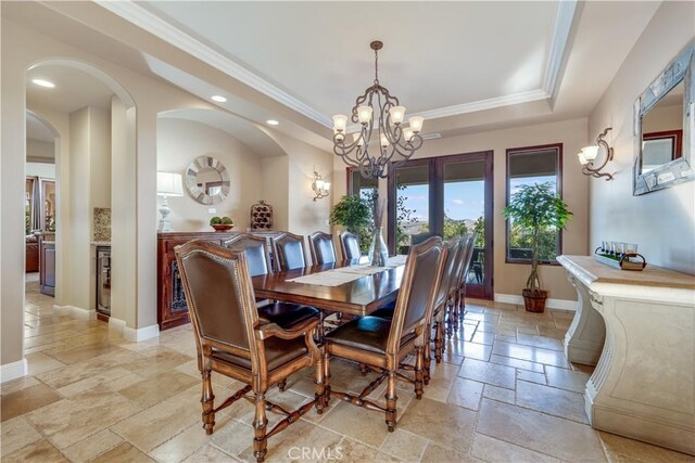 dining area with an inviting chandelier, ornamental molding, and a raised ceiling