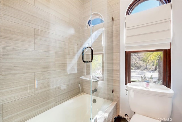 bathroom with bath / shower combo with glass door and toilet