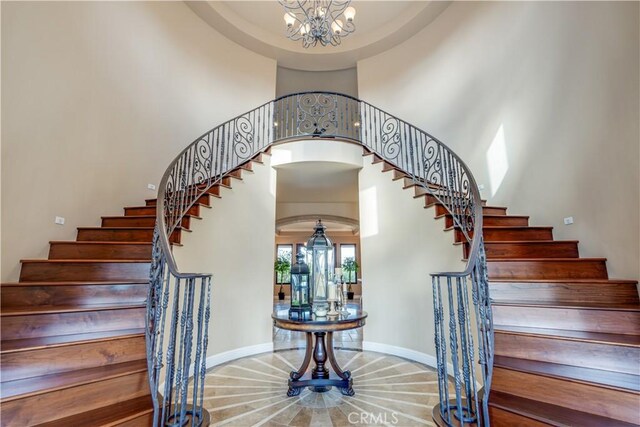 stairway with an inviting chandelier and a high ceiling