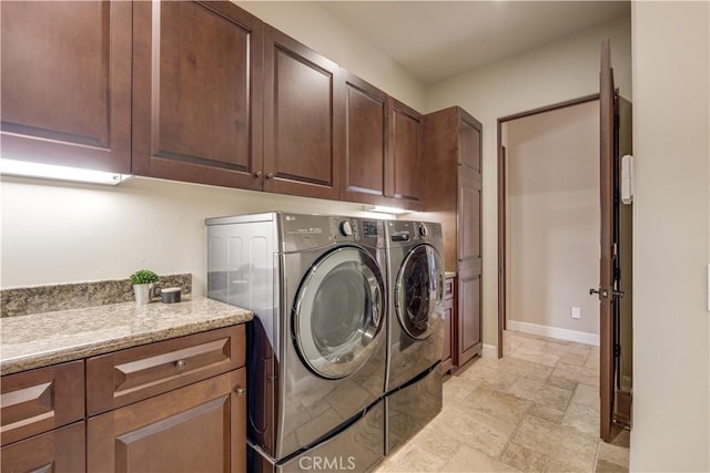 clothes washing area with cabinets and washing machine and clothes dryer