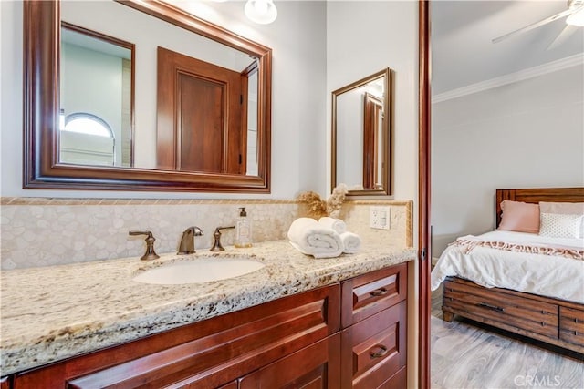 bathroom with backsplash, hardwood / wood-style flooring, ornamental molding, vanity, and ceiling fan