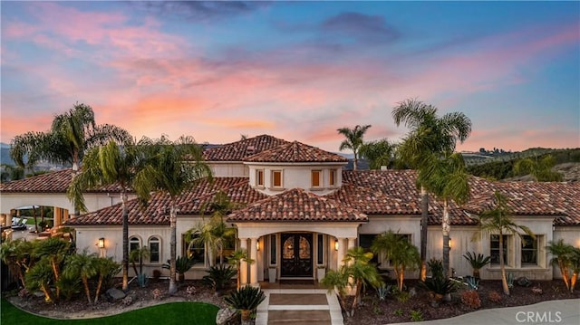 mediterranean / spanish-style house with stucco siding, french doors, and a tile roof