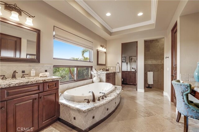 bathroom with tiled tub, vanity, crown molding, and a tray ceiling