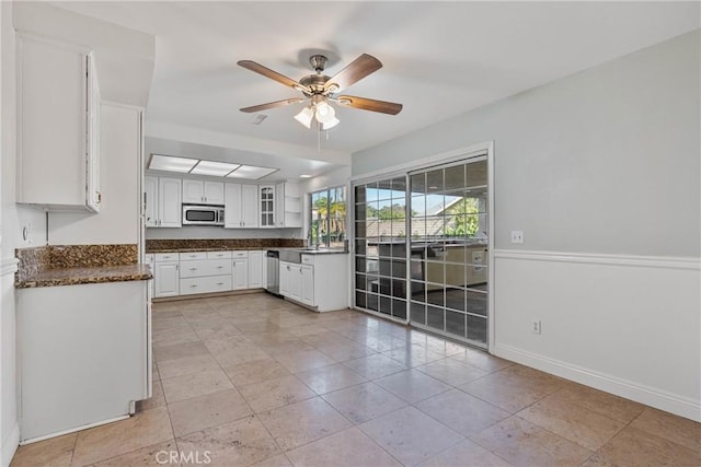 kitchen with appliances with stainless steel finishes, white cabinetry, sink, light tile patterned floors, and ceiling fan