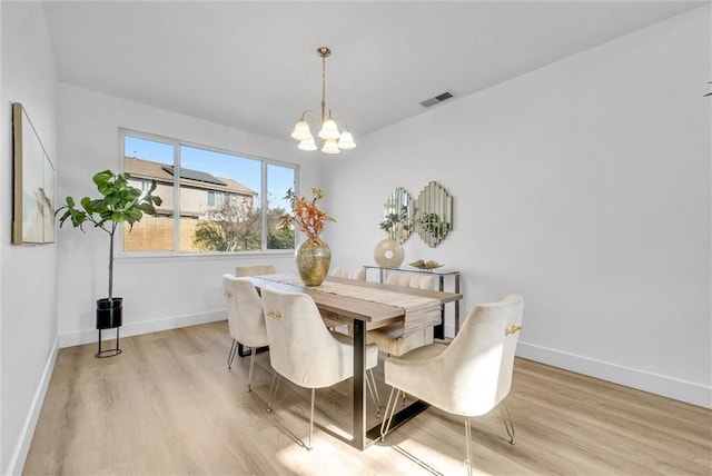 dining area with a notable chandelier and light hardwood / wood-style flooring