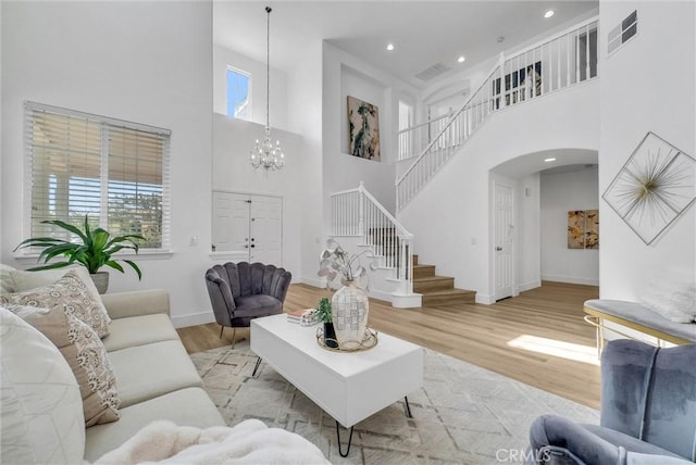 living room with a high ceiling, an inviting chandelier, and light hardwood / wood-style floors