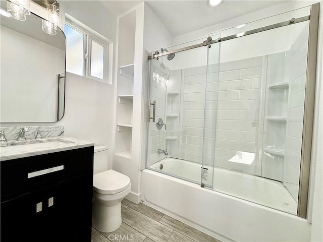 bathroom with toilet, shower / bath combination with glass door, vanity, and wood finish floors