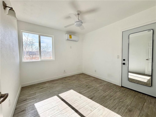 spare room featuring a wall unit AC, wood tiled floor, baseboards, and ceiling fan